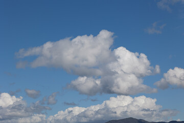 Fototapeta premium White cumulus clouds drifting across a vibrant blue sky