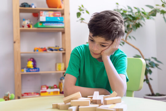 Child Showing Frustration During Learning Activity with Wooden Blocks. Difficulty with task persistence in children with autism or dyspraxia. Sensory or cognitive overload during educational tasks. 