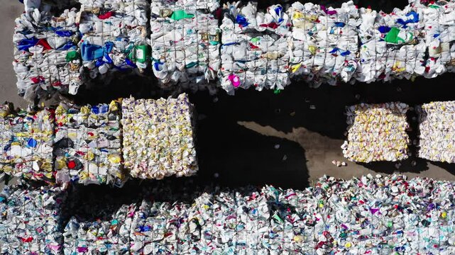 Aerial view of sorted and compressed plastic waste bales at an outdoor recycling plant, illustrating large-scale waste management operations.
