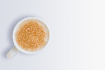 Cup of milk coffee foam in a white cup on a white background.  Monochrome and minimalism. Copy space for text. Top view.