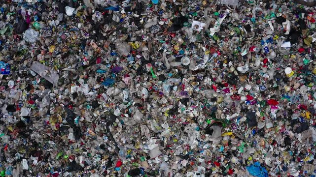 Aerial close-ups of a landfill site showing waste piles, unprocessed garbage, and plastic litter across terrain, including dirt roads and sorting zones.
