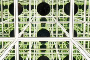 Abstract background of an infinity room exhibition featuring geometric white lines and numerous reflected black circular shapes.