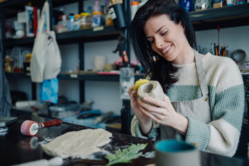 Ceramist using sponge for smoothing clay vessel in workshop