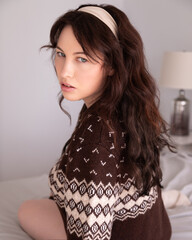 Portrait of a 30-year-old Canadian caucasian woman in a brown vintage sweater and beige headband,...