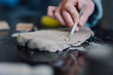 Ceramist using loop tool while working on clay slab