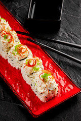Delicious sushi rolls with cream cheese and tobiko on red plate