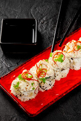 Delicious uramaki sushi rolls with tobiko and ginger on red plate