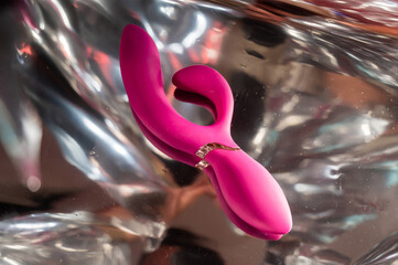 Sex toy on a metal background in the reflections of light. 