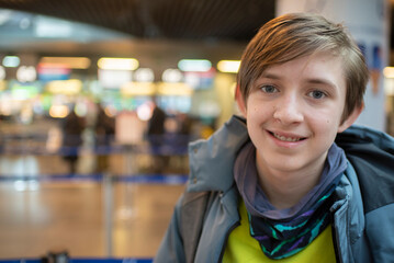 portrait of 12 year old boy in grey jacket at airport	