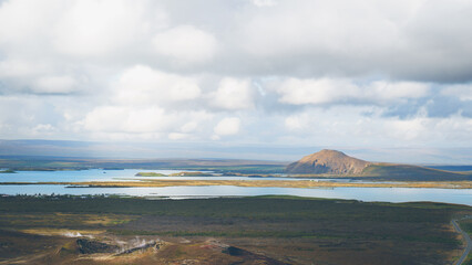 Panoramic view of Lake Mývatn in North Iceland with volcanic hills, wetlands, and geothermal steam. Ideal for travel, geology, climate, and natural heritage themes.