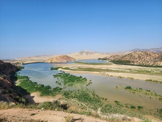 A Scenic River Flowing Through Arid Hills and Green Vegetation, Algeria