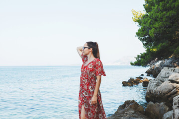 A woman is enjoying a beautiful and scenic coastal view while wearing a summer dress