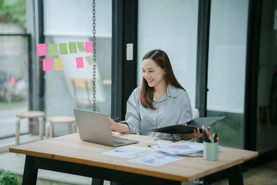 Attractive asian businesswoman sitting working on laptop thinking new idea at office. - Powered by Adobe