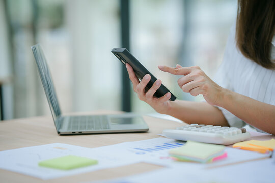 A close-up of an Asian woman holding the credit card and her smartphone while sitting indoors