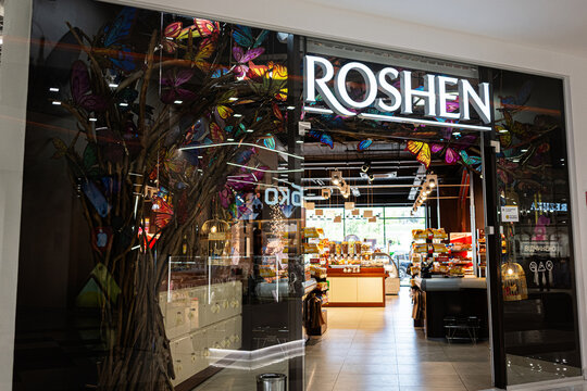 Storefront Roshen with decorative elements and illuminated signage displaying various goods