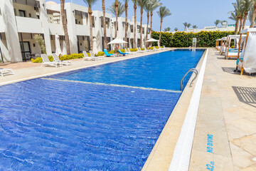 Summer seaside relax mood travel vacation a luxurious pool hotel interior for a summer holiday in warm countries. Beautiful tropical beach hotel resort with swimming pool, sun loungers palm trees
