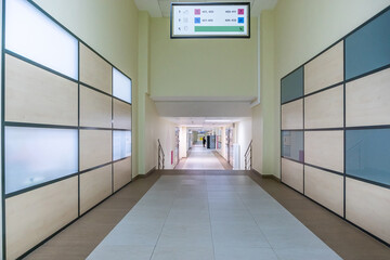 A long bright corridor in a modern office center. Walls with frosted glass inserts.