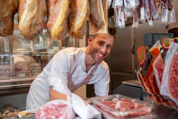 Butcher smiling while preparing meat in butcher shop