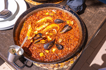Fideua, spanish seafood paella with noodles, shrimps and mussels, cooking in a paella pan