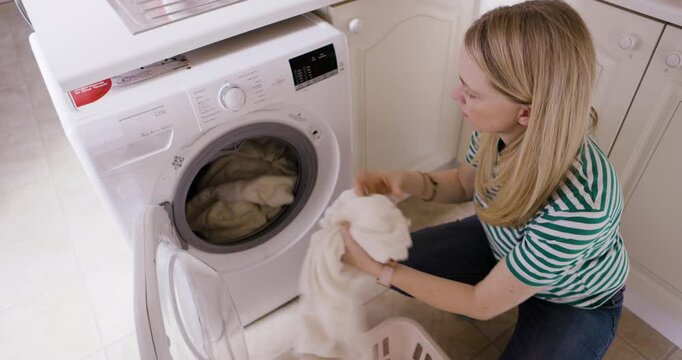 Cleaning, washing machine and woman with laundry basket in home to remove fabric, linen or clothing top view. Housekeeping, hygiene and female take out fresh clothes from electrical dryer technology