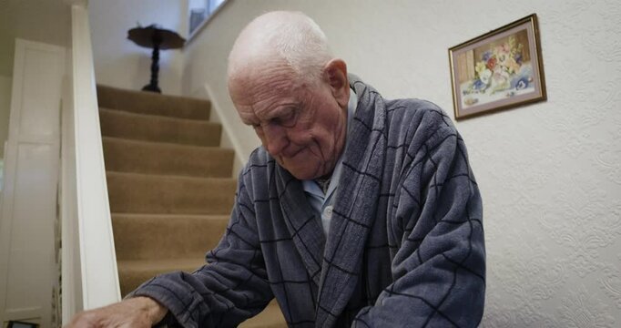 Senior man, climbing and down steps in a home, slow and careful while holding railings for balance. Retirement, frail care and elderly man having trouble walking on steps of care facility or house