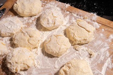 Irregularly shaped dough pieces dusted with flour rest on a wooden surface, ready for baking or cooking.