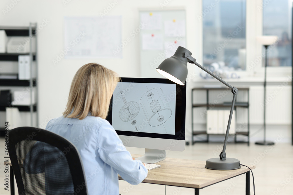 Poster technician making digital engineering drawing on computer at desk in office, back view