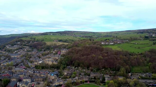 aerial drone tracking shot of the town of hebden bridge showing buildings and roads with calder valley hills in the background