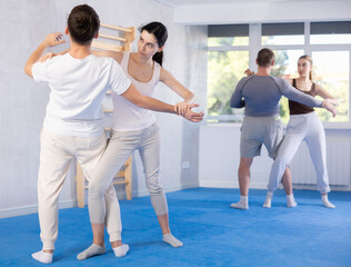Obraz premium Young woman and young guy training self-defense techniques in studio..