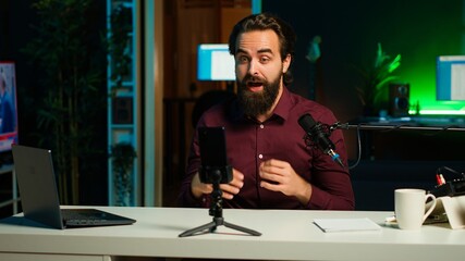 Happy media star using smartphone on tripod to film vlog channel intro for online streaming...