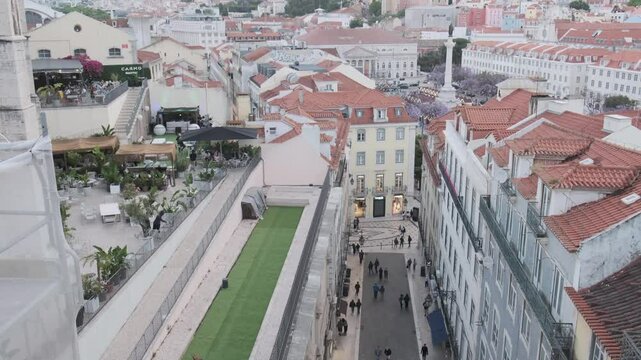 Tourists and locals walking down rua augusta in lisbon, portugal, with the rua augusta arch visible in the distance and the city skyline beyond