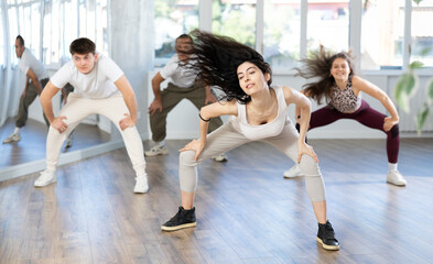 Obraz premium Group of young men and women rehearsing hip hop dance in studio
