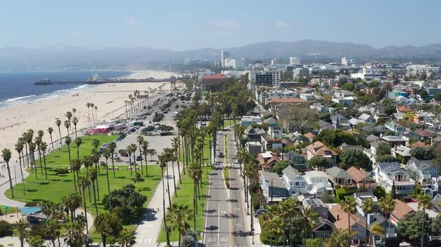 Aerial pullback shot of Santa Monica Los Angeles beach coast, palm trees, homes