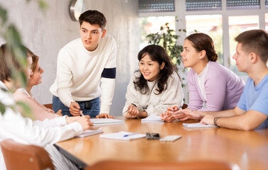 Young male tutor teaching group of students in college