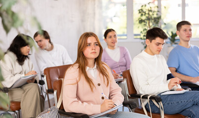 Young female student diligently attending lesson in college