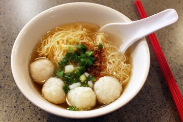 Fish ball noodles are a staple of Hong Kong street food consisting of chewy fish balls in a savory broth accompanied by noodles