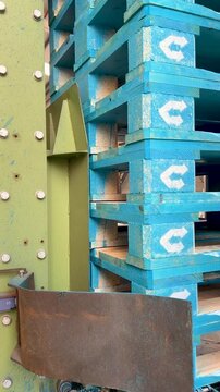 Robotic industrial arm methodically arranging blue painted pallets, demonstrating precision manufacturing workflow in contemporary logistics warehouse setting