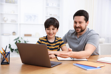 Obraz premium Father helping his son with homework at wooden table indoors