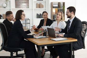 Coworkers working together at wooden table in office