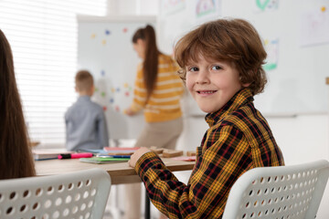 Cute boy at desk during lesson in school