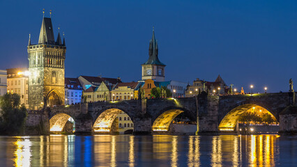 The Charles Bridge day to night timelapse over the Vltava River reflected in water in Prague, Czech...