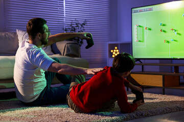 Father and his son playing video game on floor at home © New Africa