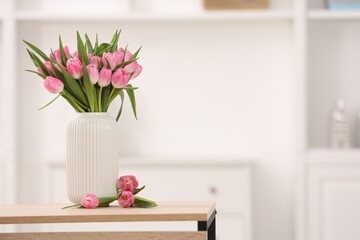 Bouquet of beautiful tulips in vase on wooden table indoors, space for text