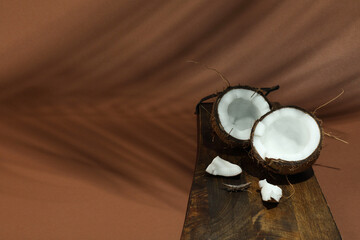 Fresh coconut and shadow cast by tropical palm on light brown background, closeup. Space for text