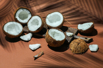 Fresh coconuts and shadow cast by tropical palm on light brown background