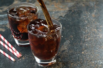 Pouring refreshing cola into glass on color marble table, closeup. Space for text