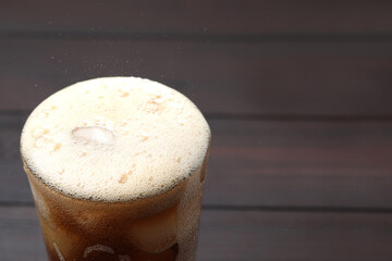 Refreshing cola in glass on wooden table, closeup. Space for text