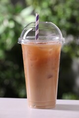 Tasty iced coffee on white table against blurred background