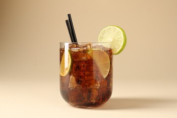 Tasty Cuba Libre cocktail in glass on beige background