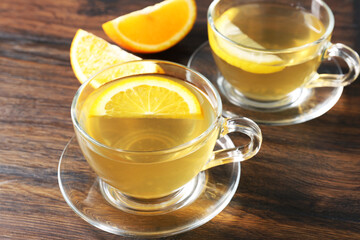 Aromatic fruit tea with orange and lemon in glass cups on wooden table, closeup